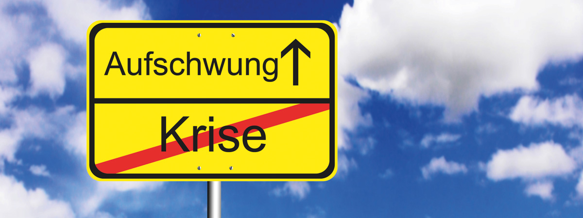 Zeigt ein Stadtausfahrtsschild unterteilt in oben 'Aufschwung' und unten rot durchgestrichen 'Krise'