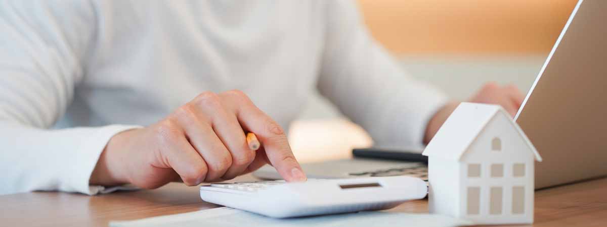 close up young man hand press on calculator to check and summary expense of home loan mortgage for refinance plan , people lifestyle concept