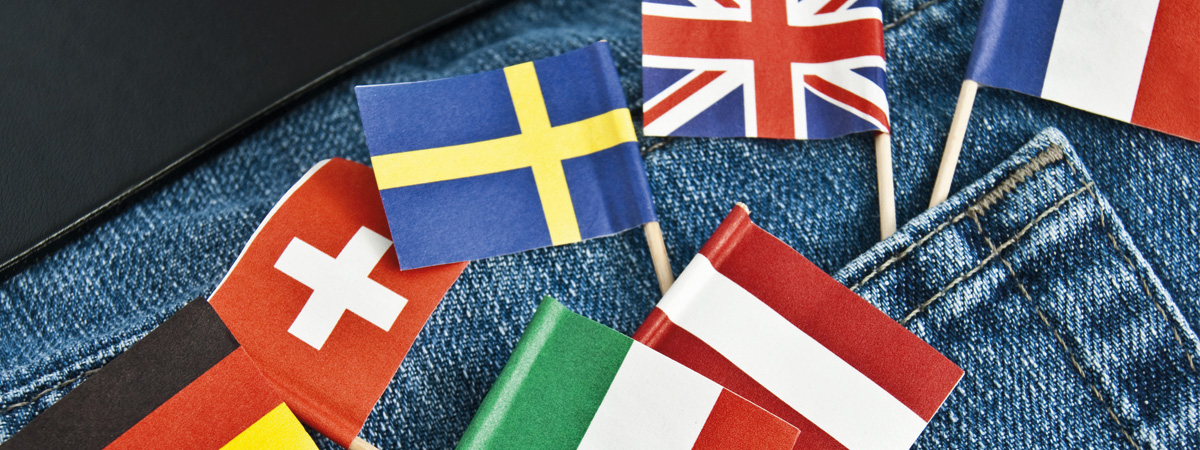 Nahaufnahme kleiner Papierflaggen der Länder Deutschland, Schweiz, Italien und Österreich eingesteckt in einer Hosentasche