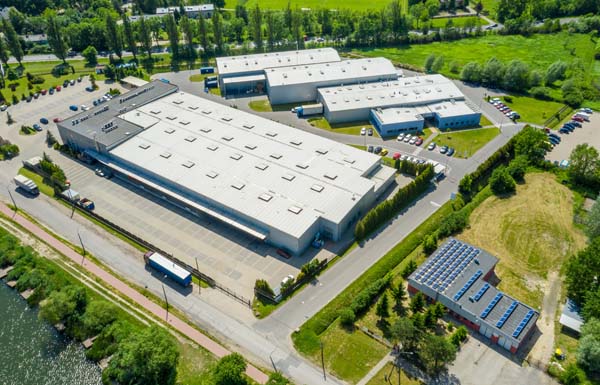 Aerial view of goods warehouse. Logistics center in industrial city zone from above. Aerial view of trucks loading at logistic center. View from drone.